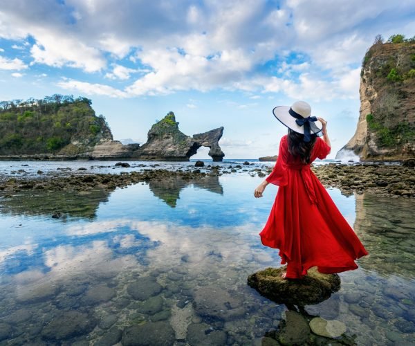 Woman standing on the rock at Atuh beach, Nusa penida island in Bali, Indonesia.